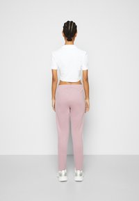 Vit kort t-shirt med korta ärmar, kombinerad med ljusrosa joggers. Har en avslappnad passform och elastisk midja. Vita sneakers fulländar looken.