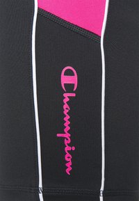 Černé sportovní šortky s růžovými akcenty a bílým prošitím. Na boku mají výrazné růžové logo "Champion". Texturovaná tkanina.