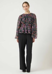 Svart blomstrete peplum-topp med lange, puffermer, med flerfargede blomster og rynket halslinning, kombinert med svarte vidbukser.