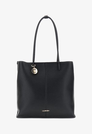 Musta teksturoitu nahkakassi pitkien kahvojen kanssa, kullasta valmistettu pyöreä riipus ja pieni kultainen "CARENOR"-logo alhaalla keskellä.