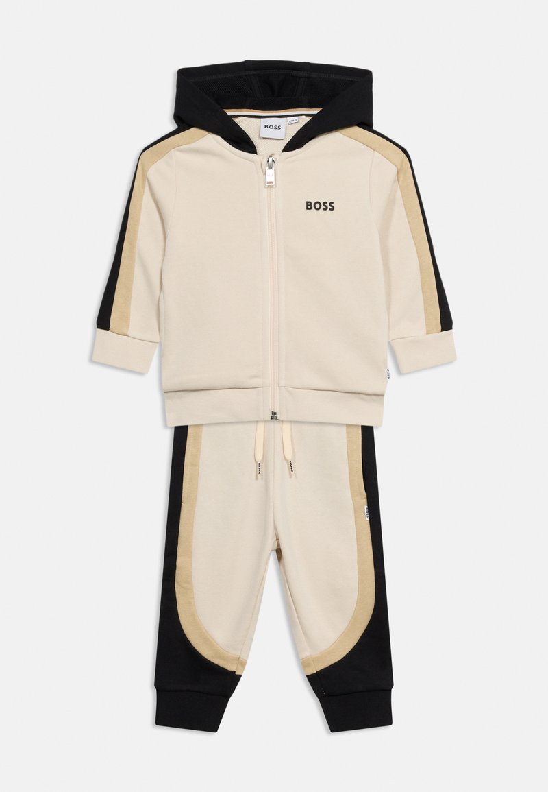 Σετ φόρμας για νήπιο σε μπεζ, μαύρο και ταμπά με ζακέτα με φερμουάρ και παντελόνι με ελαστική μέση, με το λογότυπο BOSS στο στήθος και στο μπατζάκι του παντελονιού.