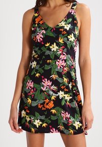 Blumenkleid mit V-Ausschnitt und verstellbaren Trägern. Schwarzer Hintergrund mit bunten Blumen in Pink, Orange und Grün. Weicher, leichter Stoff.