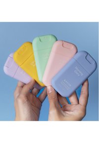 Cinque disinfettanti per le mani in colori pastello: giallo, verde, rosa, viola e blu. Ognuno ha una finitura liscia e opaca e presenta del testo sull'etichetta.