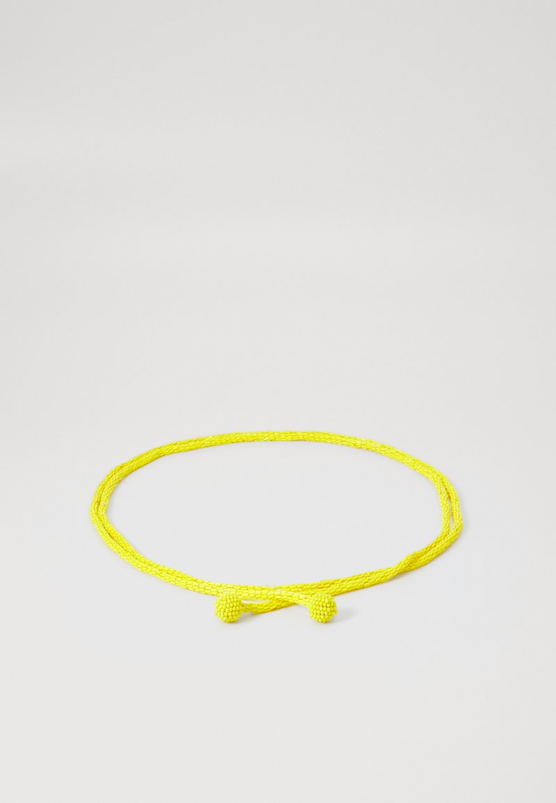 Lys gul perlekæde med en snoet design og knude detalje foran, der har en glat overflade og jævnt mellemrum mellem perlerne.