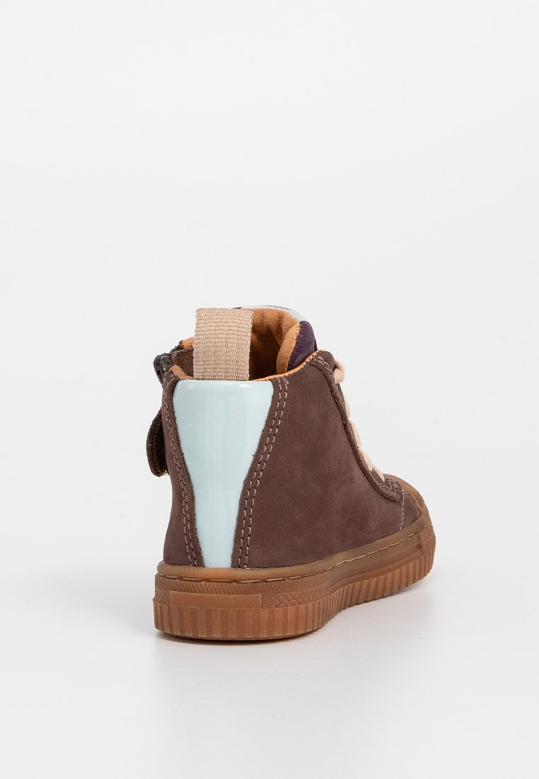 Sneaker alta in suede marrone con linguetta beige e patch sul tallone azzurro chiaro, lacci beige e suola in gomma color caramello su sfondo bianco.