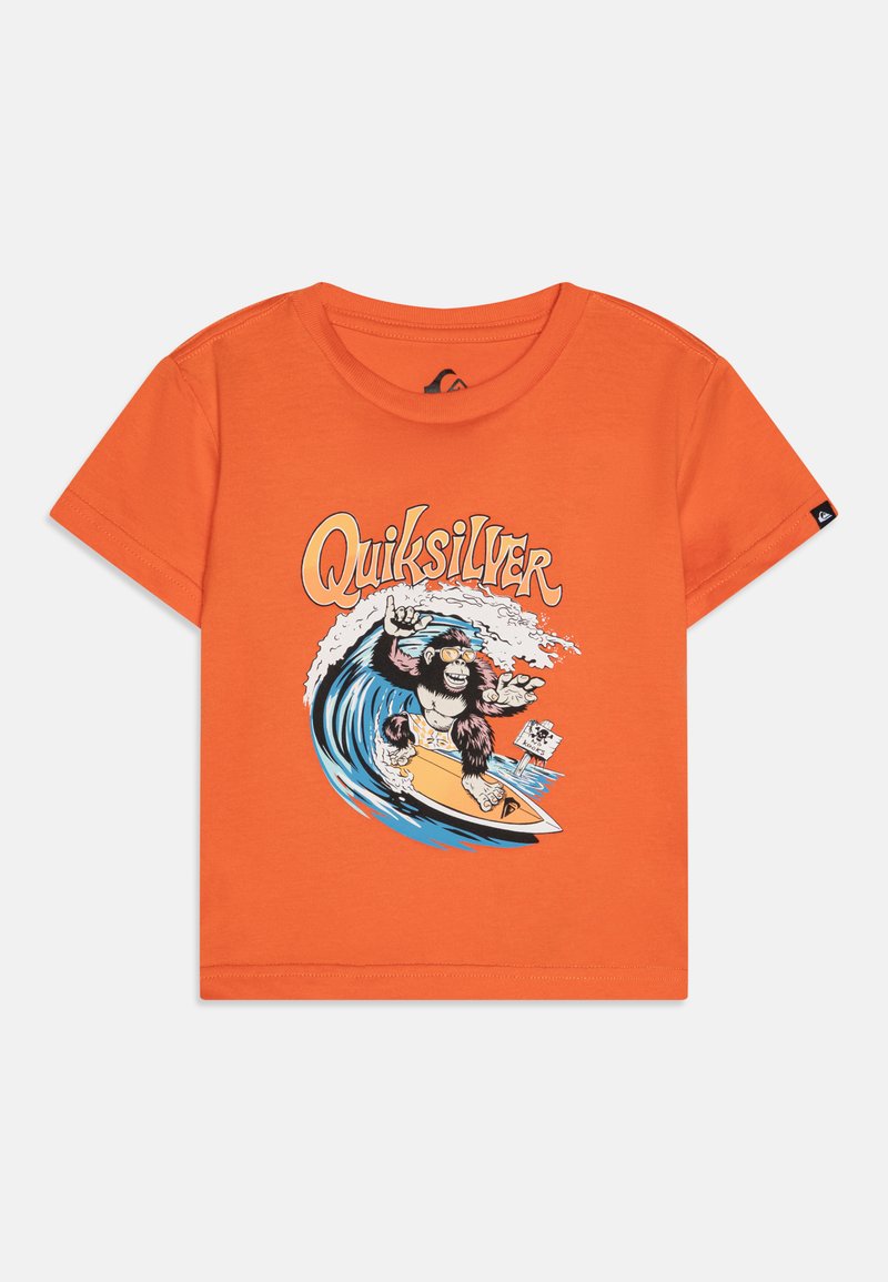 Oranžové bavlněné tričko s grafikou opice surfující na vlně, s textem "Quiksilver" nahoře v bílé a žluté barvě. Krátké rukávy.