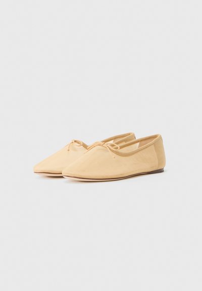 Light beige flat shoes with a pointed toe design, soft fabric upper, discreet lacing detail, and a slim rubber sole.