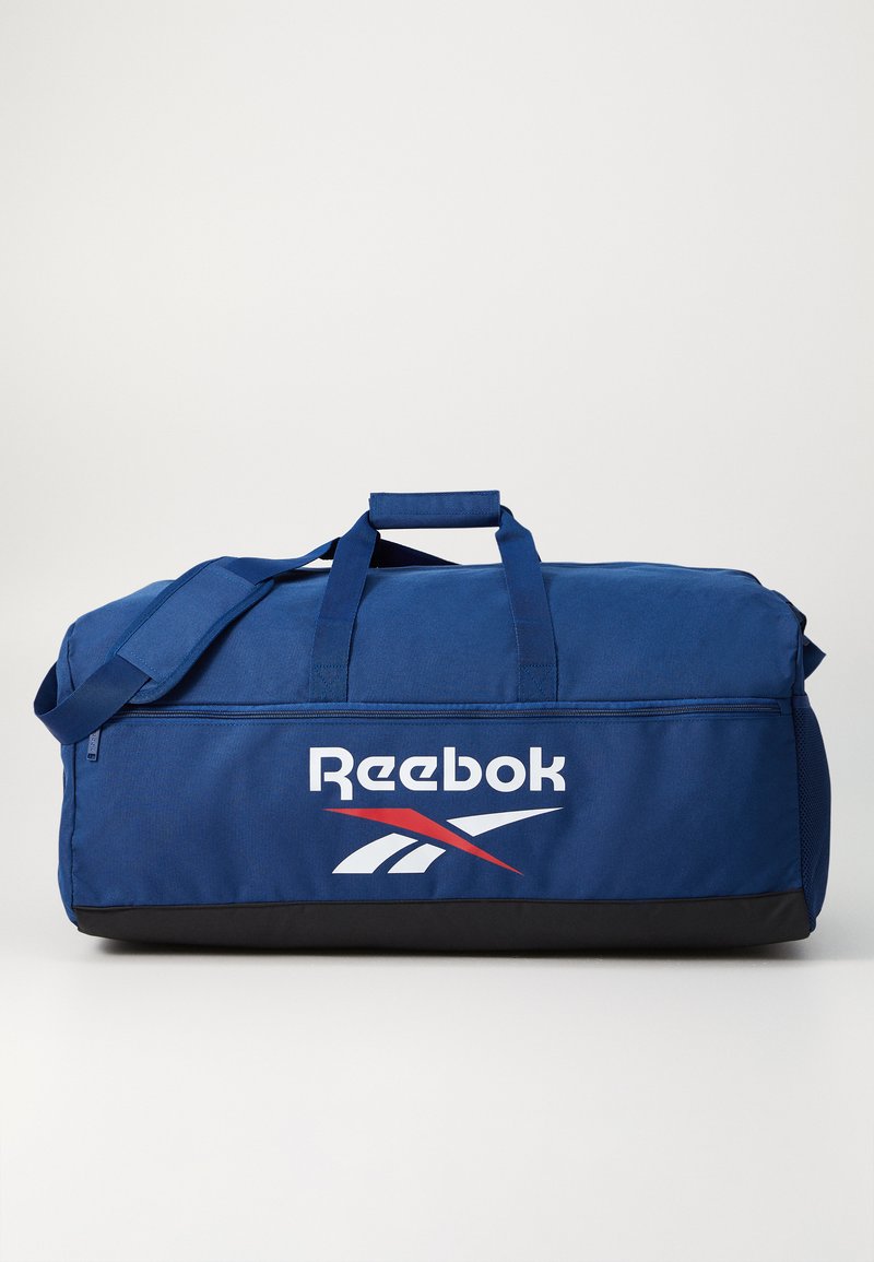 Zils sporta soma, izgatavota no izturīga auduma, ar melnu apakšu, divām augšējām rokturiem un Reebok logotipu ar sarkaniem un baltiem akcentiem.