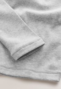 Light grey ribbed long sleeve fabric with visible cuff and hem stitching on a flat surface.