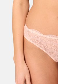 Lace hipster onderbroekjes in zachtroze met golvende randen en een delicate bloemenpatroon, gemaakt van rekbare, lichte stof.