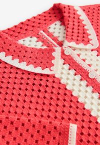 Cardigan all'uncinetto corallo con accenti bianchi, caratterizzato da un collo a camicia, chiusura a bottoni e un motivo a griglia testurizzato su tutta la superficie.