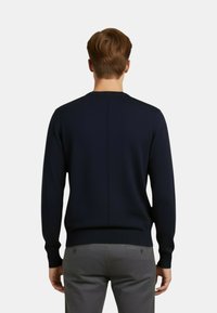 Maglione in maglia blu navy con scollo rotondo, polsini e orlo a coste e dettaglio di cucitura centrale sul retro. Tessuto a tinta unita, senza motivi.