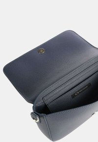 Borsa in pelle blu navale con finitura testurizzata, chiusura a scatto magnetica e un'etichetta interna con il marchio. Lo stile aperto mostra un interno spazioso.