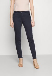 Navyblauwe slim-fit jeans van een katoenmix, met zijzakken en een knoopsluiting. Gepaard met neutrale sandalen.