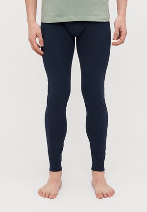 Mørkeblå leggings lavet af blødt, elastisk stof med en slank pasform, designet til komfort og fleksibilitet, båret med en lys grøn top.