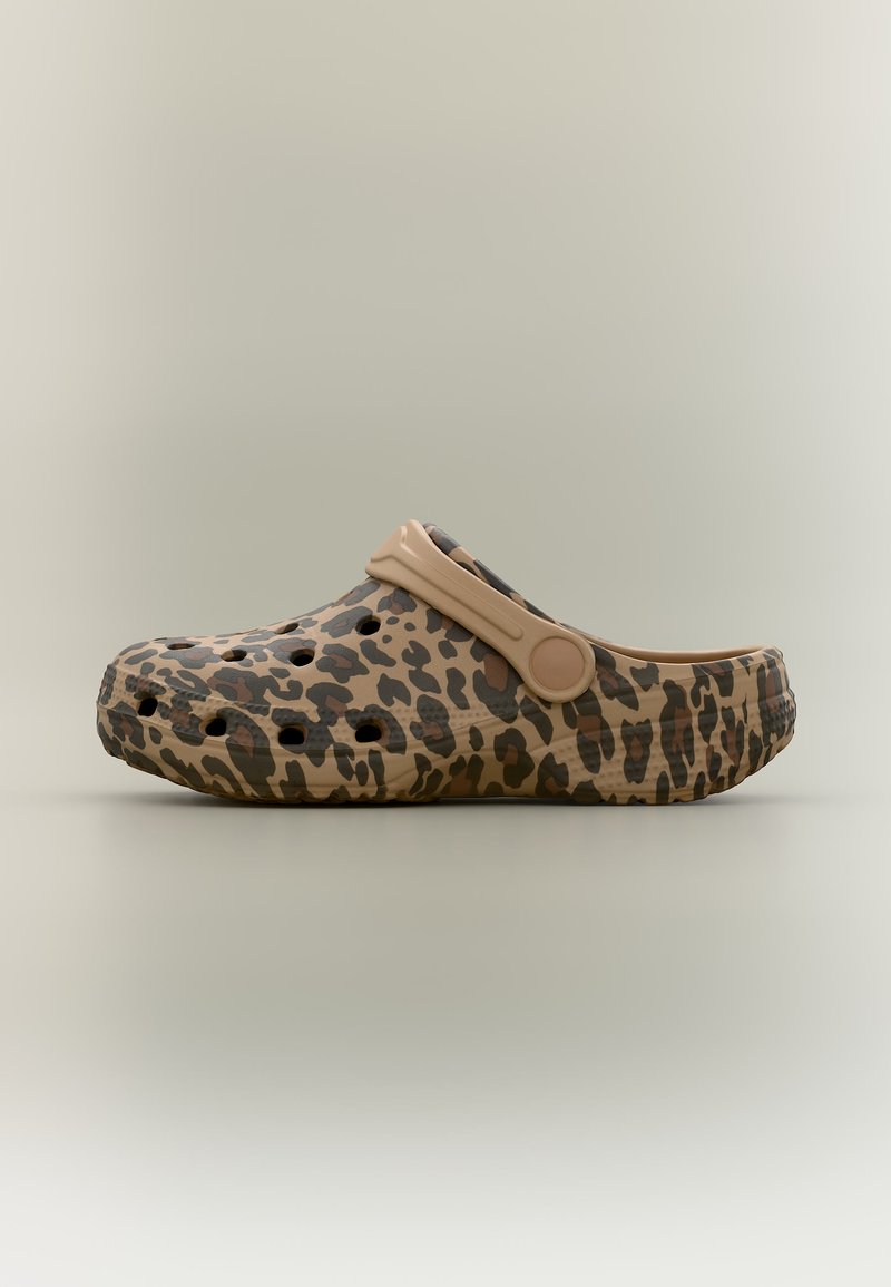Sabots marron clair avec imprimé léopard marron foncé, trous de ventilation et une bride au niveau du talon sur un fond neutre.