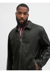 Musta nahkatakki vetoketjulla, kauluksella ja kahdella sivutaskulla. Pinnassa on hieman karheaa struktuuria näkyvine ompeluineen.