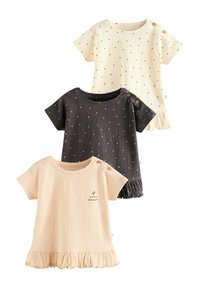 Tres camisetas de manga corta de canalé en crema, beige y gris oscuro, con lunares, dobladillos con volantes y acentos de botones cerca de los hombros.