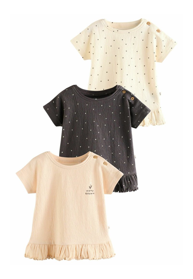 Tres camisetas de manga corta de canalé en crema, beige y gris oscuro, con lunares, dobladillos con volantes y acentos de botones cerca de los hombros.