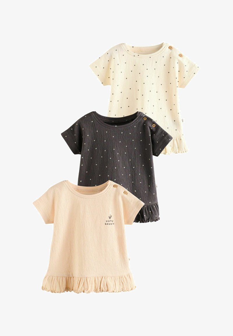 Drei kurzärmelige Kleinkind-Shirts in Creme, Schwarz mit kleinen Herzen und Beige mit "Home Grown" Text, alle mit Knopfdetails an einer Schulter.