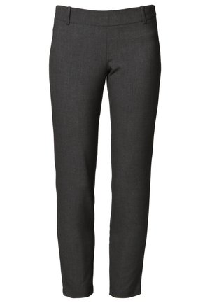 Femme portant un blazer noir ouvert, un chemisier blanc, un pantalon gris slim, des ballerines noires et un sac à main noir avec une bandoulière chaîne.