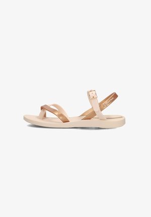 Sandali piatti color bronzo e oro metallico con cinturini incrociati, fibbia regolabile alla caviglia e suola in gomma testurizzata. Progettati per un uso casual.
