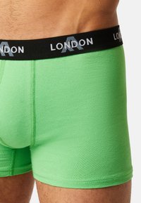 Green cotton boxer shorts with a fitted design and black elastic waistband featuring "LONDON" text in white and gray.