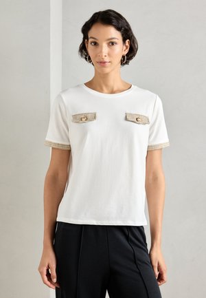 Witte t-shirt met korte mouwen en ronde hals, met textuurbeige zakken met gouden knopen aan de voorkant en geruite accenten op de mouwen.