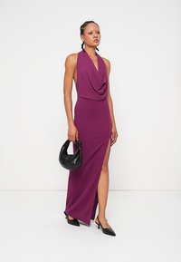 Δαμασκηνί halter maxi φόρεμα με ραμμένο ντεκολτέ, ψηλή σχισμή αριστερά, απαλό υφή, συνδυασμένο με μαύρη τσάντα και παπούτσια με μυτερή μύτη.