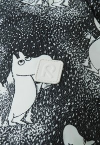 Czarny i biały materiał z postaciami Muminków na tle o teksturze, z białą prostokątną metką showcasing stylizowane logo "R".