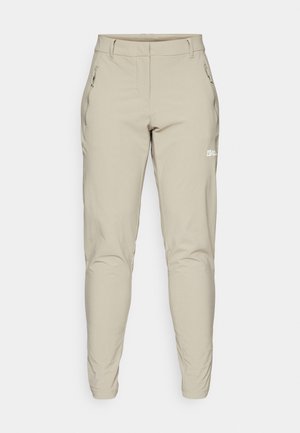 Beige, slim-fit buitenbroek met een gladde textuur, voorzien van zijden ritszakken en een klein logo op de dij. Aangepaste enkelopeningen.