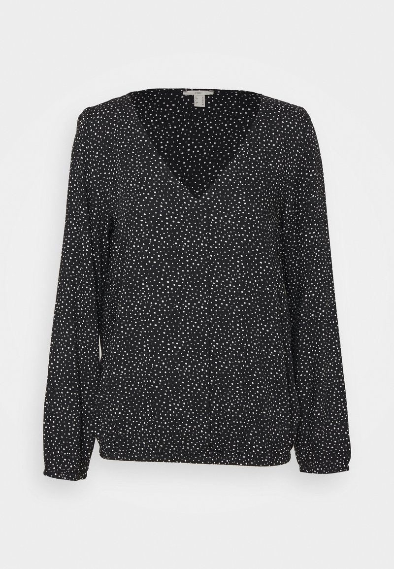 Blouse noire à manches longues avec col en V et petits pois blancs répartis uniformément sur le tissu.