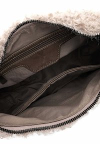 Borsa color crema con un rivestimento esterno in pelliccia riccia e testurizzata. L'interno è foderato in tessuto scuro con una tasca con zip e dettagli in pelle.