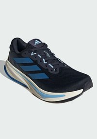 Zapatilla deportiva negra con acentos azules, parte superior de malla y suela acolchada. Presenta un logo a rayas y un sistema de cordones para un ajuste seguro.