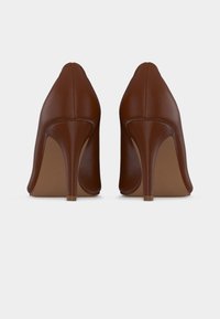 Καφέ δερμάτινα ψηλοτάκουνα με μυτερό μύτη και λεπτό τακούνι στιλέτο. Λείο υλικό, ελάχιστη ραφή και σχεδιασμός σε μονόχρωμο χρώμα.