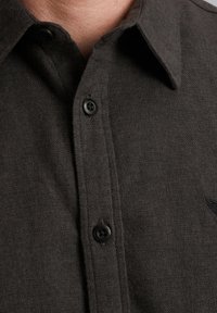 Donkergrijze button-up shirt gemaakt van gestructureerde stof, met een puntige kraag en een klein geborduurd logo nabij de schouder.