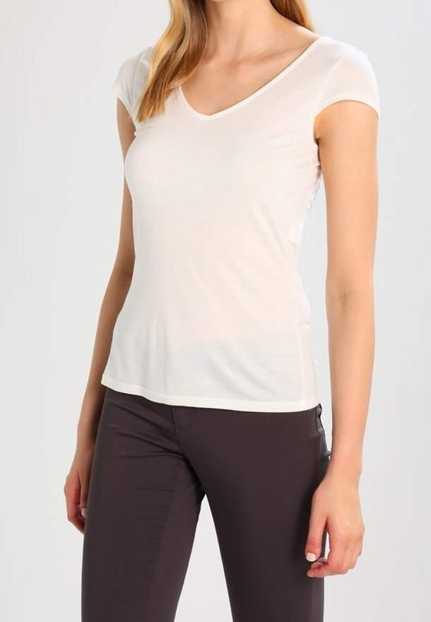 Biała koszulka polo z dekoltem w serek, wykonana z lekkiego, gładkiego materiału. Posiada krótkie rękawy i dopasowany krój. Zestawiona z ciemnymi brązowymi spodniami.