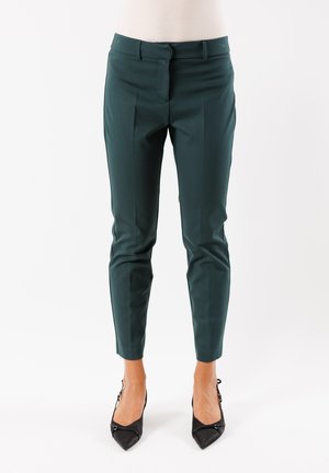 Pantaloni su misura in turchese con una texture liscia, vestibilità slim e piega ben definita. Abbinati a tacchi a punta neri, con un accento lucido.