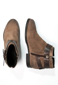 Stivaletti alla caviglia in suede marrone con dettagli in pelle scura, chiusura laterale con zip e punta arrotondata. Superficie strutturata e design con tacco basso.
