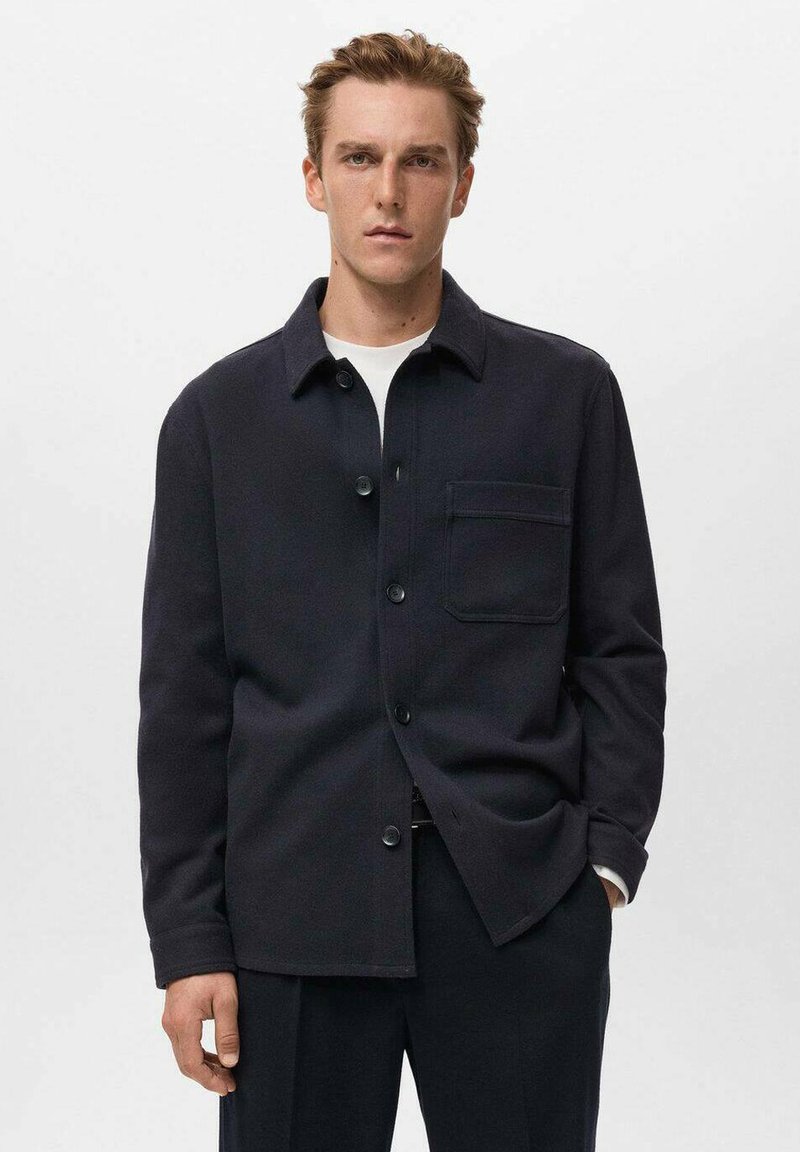 Giacca in tessuto testurizzato di colore blu navy con taschino sul petto, colletto aperto e chiusura frontale con bottoni. Design semplice e moderno.