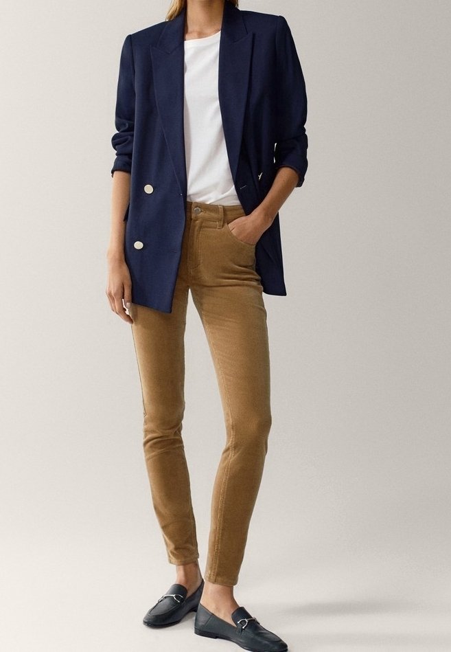 Navy kaksirivin takki, valkoinen t-paita, vaaleanruskeat corduroy-housut ja mustat loafers-kengät. Takissa on kultaiset napit ja käännetyt hihat.