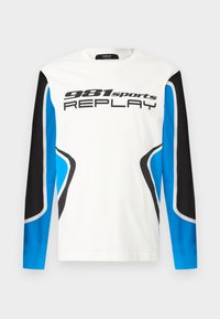 Long-sleeve sports shirt with white front, black and blue sleeve panels, and "981 sports REPLAY" logo printed across the chest.