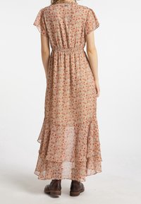 Robe maxi en tissu léger avec un motif floral orange et blanc. Elle présente des manches courtes, une taille élastique et un ourlet à plusieurs couches.