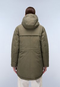 Parka imbottito verde oliva con cappuccio, caratterizzato da linee cucite e un orlo posteriore leggermente più lungo. Texture liscia e design minimalista.