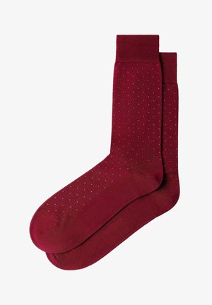 Par de calcetines burgundy con pequeños lunares blancos y puños acanalados, extendidos y superpuestos sobre un fondo blanco.