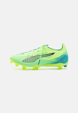 Scarpa da calcio di colore giallo-verde neon con superficie testurizzata, dettagli neri, lacci blu e design a profilo basso. Le scarpe sono sagomate per garantire una presa ottimale.