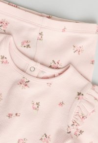 Rosa geripptes Stoff-Outfit mit kleinen Blumenmustern, Rundhalsausschnitt und Rüschensäumen, mit Druckknopfverschluss hinten.