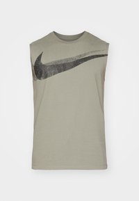 T-shirt sans manches en coton vert olive avec un grand logo noir Nike Swoosh sur la poitrine. Design simple et minimaliste.