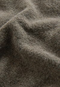 Un tessuto brown di texture mostra una superficie morbida e pelosa con un sottile motivo di tessitura, creando contorni e profondità delicati nel materiale.