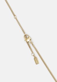 Bracelet en chaîne dorée avec un fermoir en forme de homard et une étiquette plate gravée "BOSS". La chaîne présente un design de maillons uniformes avec une finition lisse.